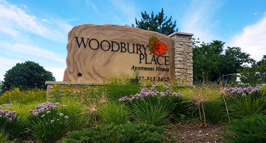 a sign for woodbury place with flowers in front of it